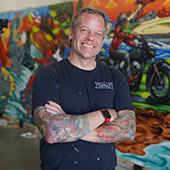 adam turman stands in front of a colorful mural