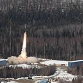 a rocket takes off from a forested area with snow
